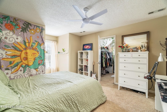 bedroom featuring a spacious closet, visible vents, light carpet, a closet, and a textured ceiling