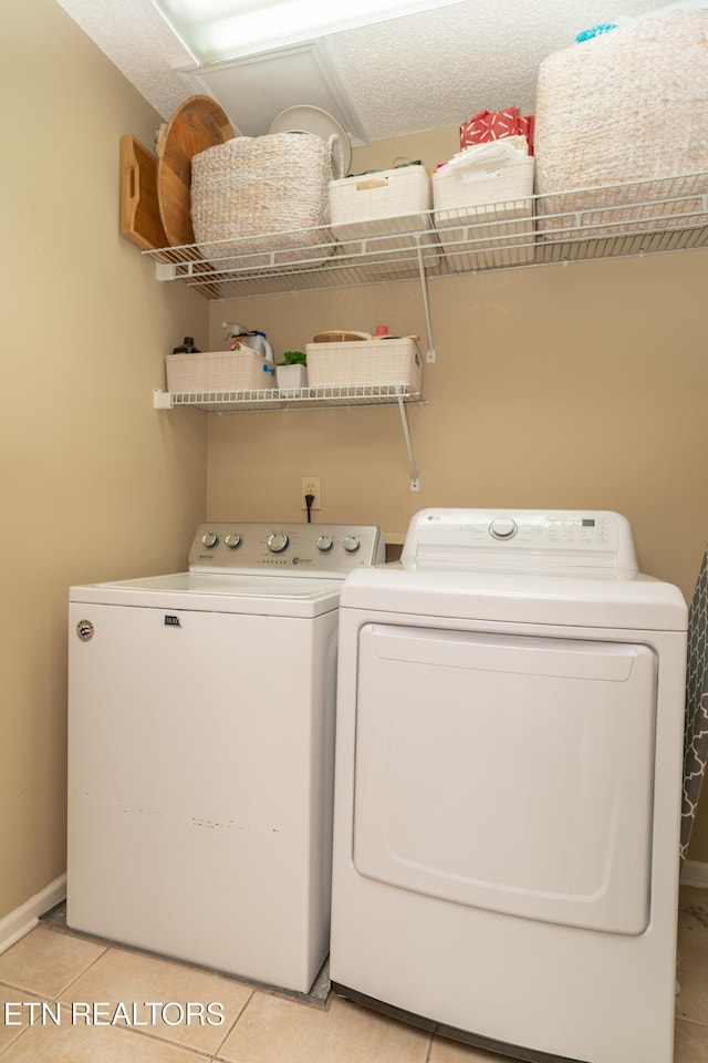 laundry area with light tile patterned floors, a textured ceiling, independent washer and dryer, and laundry area