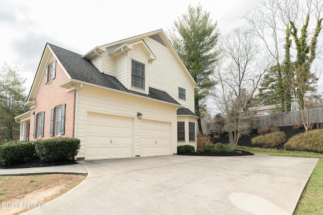 view of side of home featuring fence, roof with shingles, concrete driveway, a garage, and brick siding