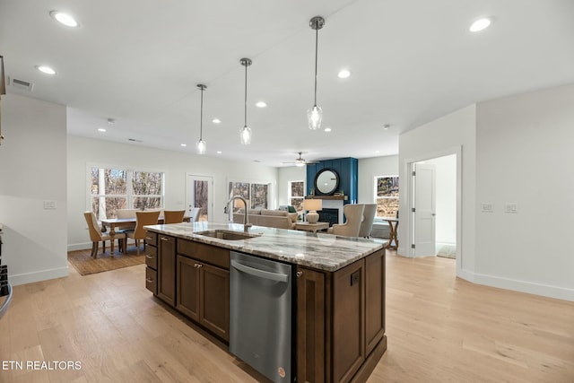 kitchen with visible vents, dishwasher, open floor plan, light wood-style floors, and a sink