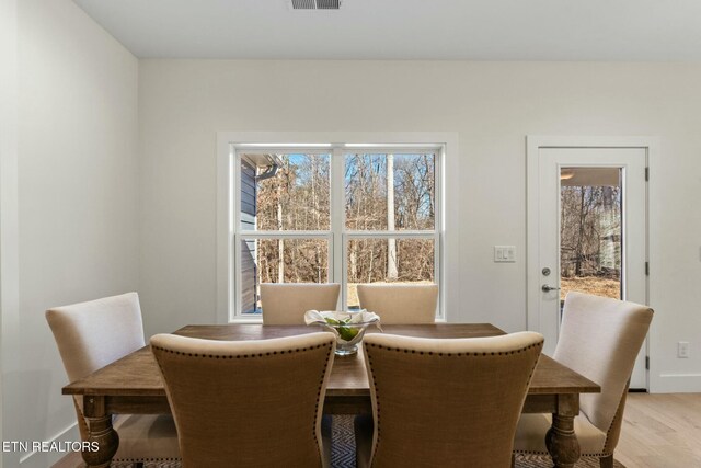 dining area featuring light wood-style floors, baseboards, and visible vents