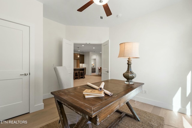 home office with baseboards, light wood-style flooring, and a ceiling fan