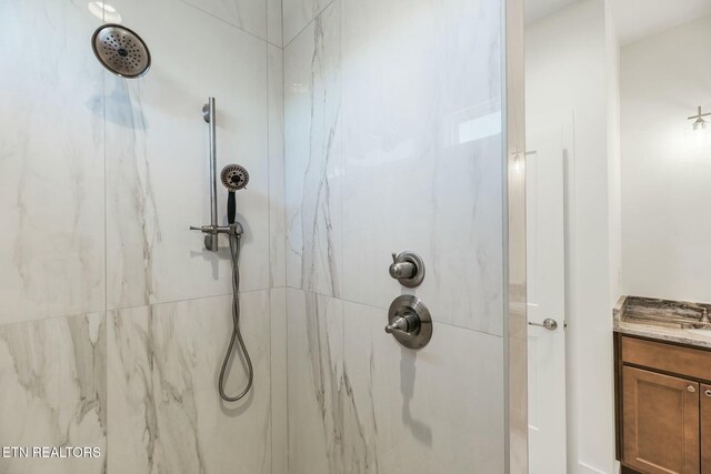 bathroom with vanity and a marble finish shower