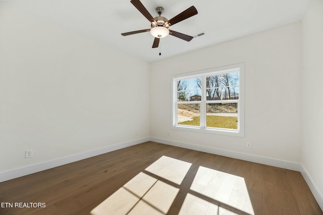 unfurnished room with ceiling fan, wood finished floors, visible vents, and baseboards