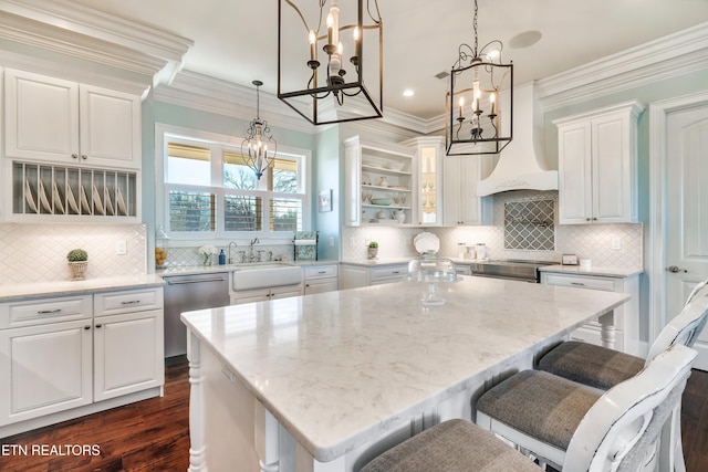 kitchen with a kitchen island, a sink, white cabinets, appliances with stainless steel finishes, and custom range hood