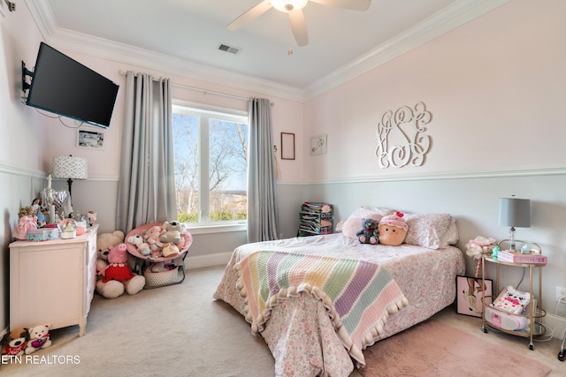 carpeted bedroom with a ceiling fan, baseboards, visible vents, and crown molding