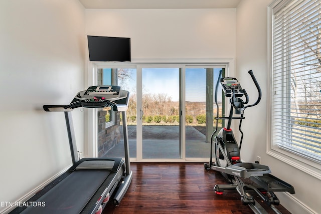 workout area featuring dark wood-type flooring and baseboards