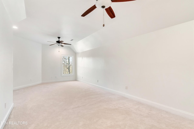 unfurnished room featuring baseboards, ceiling fan, vaulted ceiling, and light colored carpet