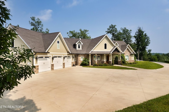 2356 Coaster Way, Sevierville, TN 37876 - craftsman-style house featuring driveway, stone siding, a porch, an attached garage, and a front lawn