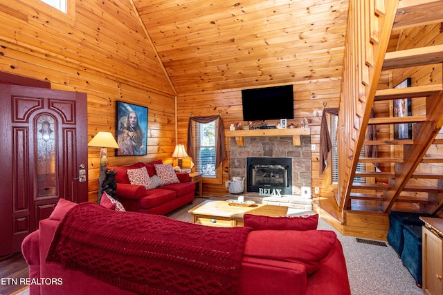 living area with stairs, high vaulted ceiling, wood walls, and plenty of natural light