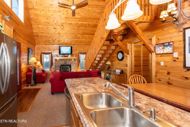 kitchen featuring carpet floors, wood walls, a fireplace, and appliances with stainless steel finishes