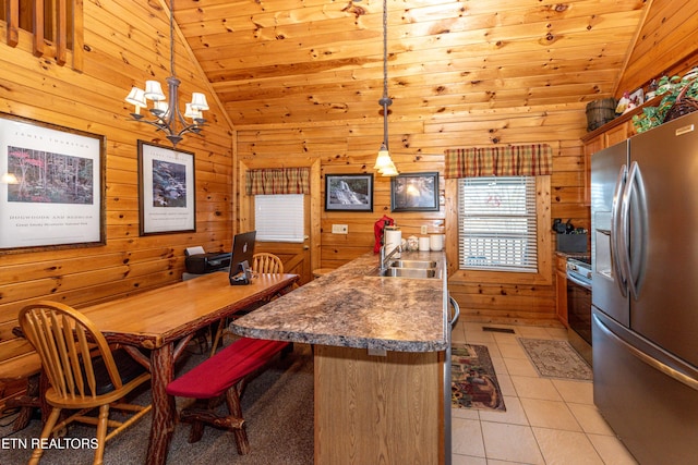 kitchen featuring appliances with stainless steel finishes, light tile patterned flooring, vaulted ceiling, and wood walls