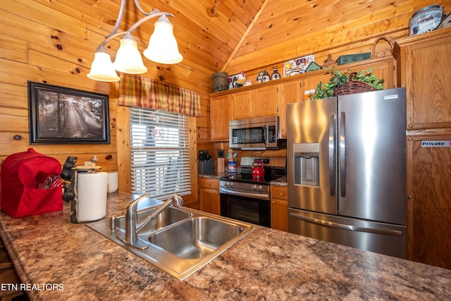 kitchen featuring brown cabinets, appliances with stainless steel finishes, vaulted ceiling, a sink, and wooden walls