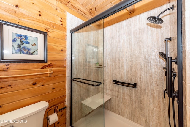 full bath with wooden walls, a shower stall, and toilet