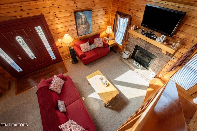 carpeted living room with a fireplace and wood walls