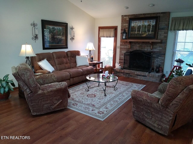 living room featuring lofted ceiling, a brick fireplace, and wood finished floors