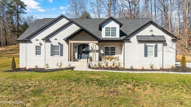 french country style house featuring brick siding and a front yard