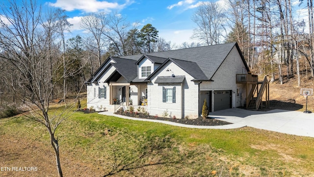 view of front of property featuring brick siding, stairway, an attached garage, a front yard, and driveway