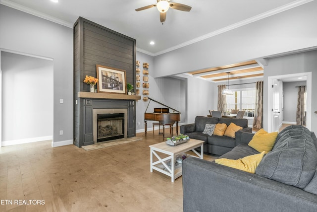 living room featuring baseboards, a ceiling fan, ornamental molding, wood finished floors, and a fireplace