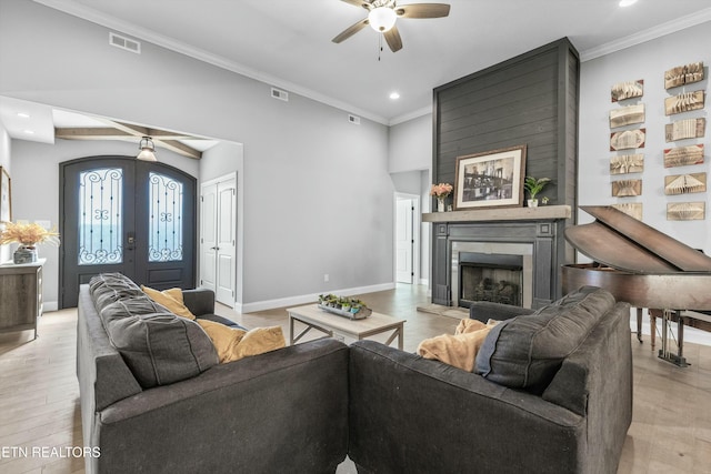 living area featuring a large fireplace, visible vents, baseboards, ornamental molding, and french doors