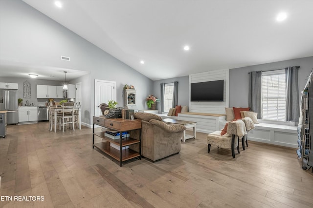 living area with recessed lighting, visible vents, vaulted ceiling, and light wood-style flooring