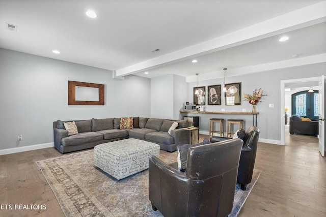 living room with recessed lighting, visible vents, beam ceiling, and wood finished floors