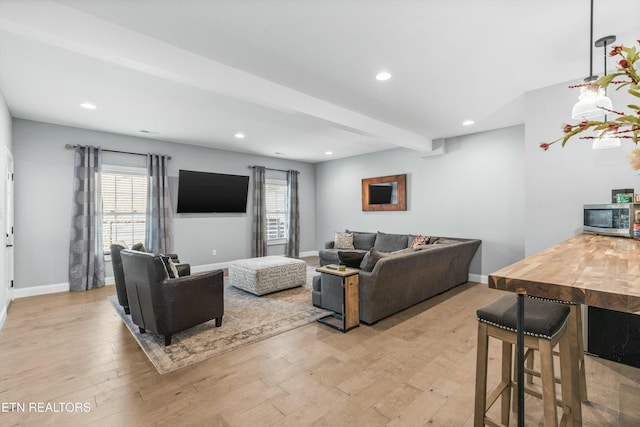 living area with beam ceiling, recessed lighting, light wood-style flooring, and baseboards