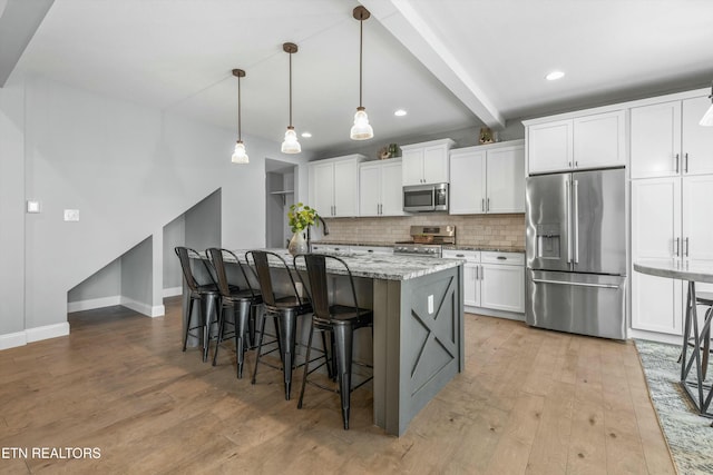 kitchen featuring stainless steel appliances, white cabinetry, backsplash, beam ceiling, and light wood finished floors