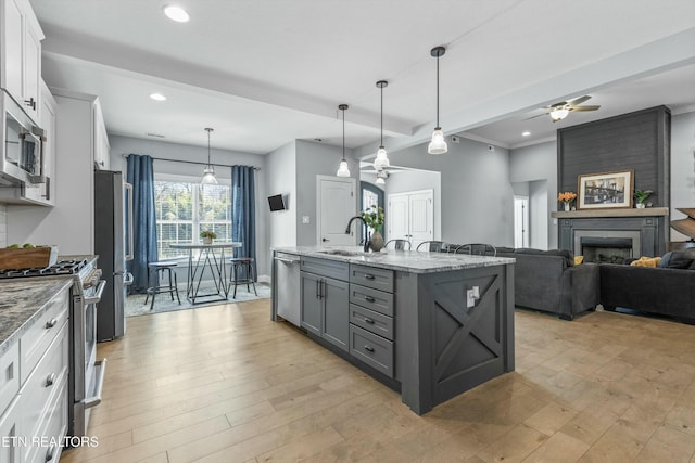 kitchen with gray cabinetry, a sink, white cabinetry, appliances with stainless steel finishes, and light wood-type flooring