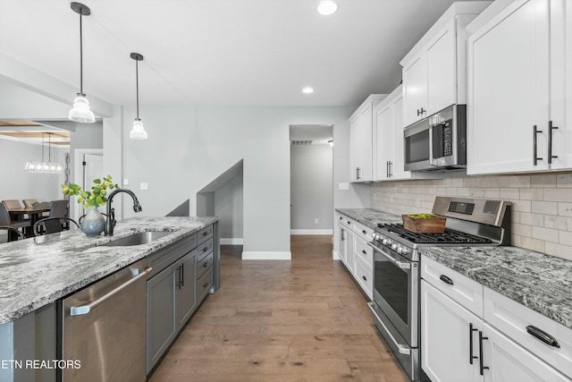 kitchen with appliances with stainless steel finishes, white cabinets, a sink, and tasteful backsplash