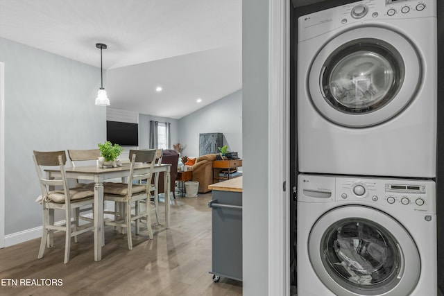 clothes washing area featuring stacked washing maching and dryer, light wood-style flooring, laundry area, and recessed lighting