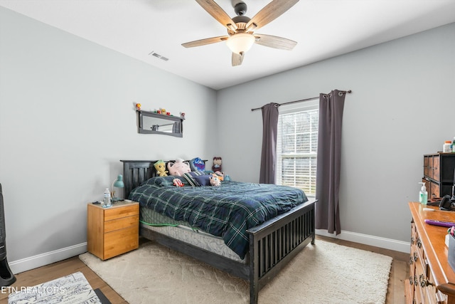 bedroom featuring a ceiling fan, light wood-type flooring, visible vents, and baseboards