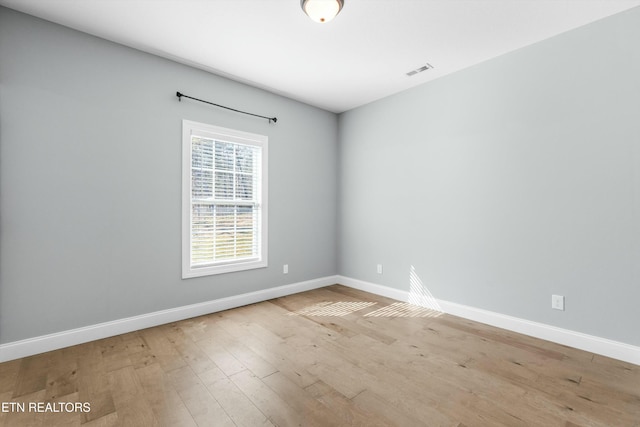 spare room featuring wood finished floors, visible vents, and baseboards