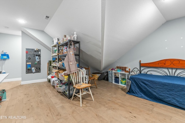 bedroom with lofted ceiling, baseboards, visible vents, and hardwood / wood-style floors