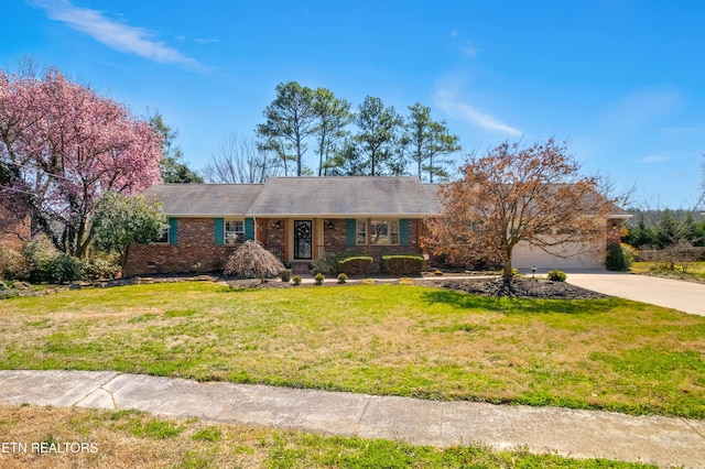 single story home featuring brick siding, a garage, a front lawn, and driveway