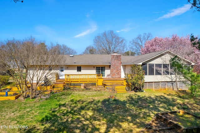 back of property with a yard, a sunroom, a garden, a wooden deck, and a chimney