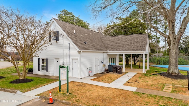 view of side of home with a patio, cooling unit, a yard, and roof with shingles