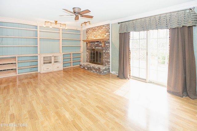 unfurnished living room with crown molding, a brick fireplace, wood finished floors, and ceiling fan