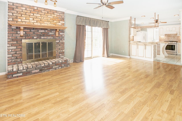 unfurnished living room featuring light wood finished floors, a brick fireplace, crown molding, and ceiling fan