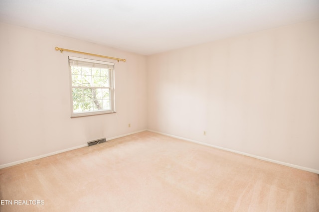 empty room with light carpet, visible vents, and baseboards