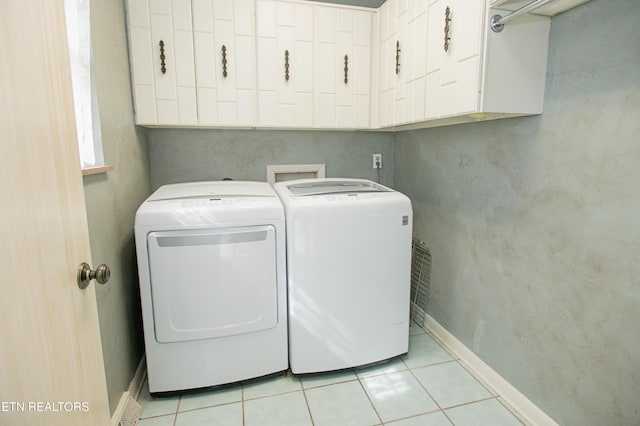 washroom featuring light tile patterned floors, cabinet space, baseboards, and washing machine and clothes dryer