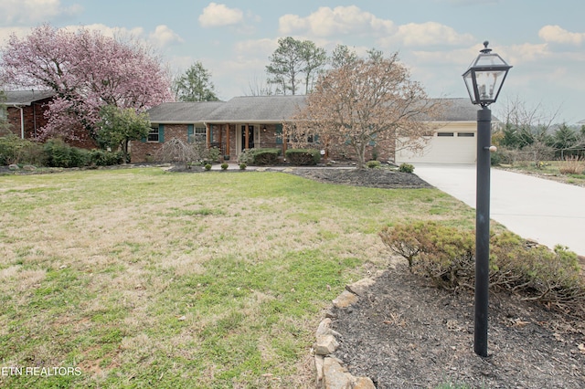 ranch-style house with brick siding, a garage, a front yard, and driveway