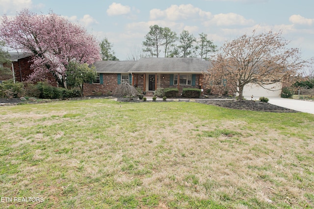 single story home with brick siding, a garage, driveway, and a front lawn