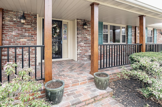 property entrance with a porch and brick siding