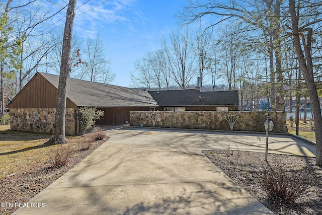 exterior space with stone siding and driveway