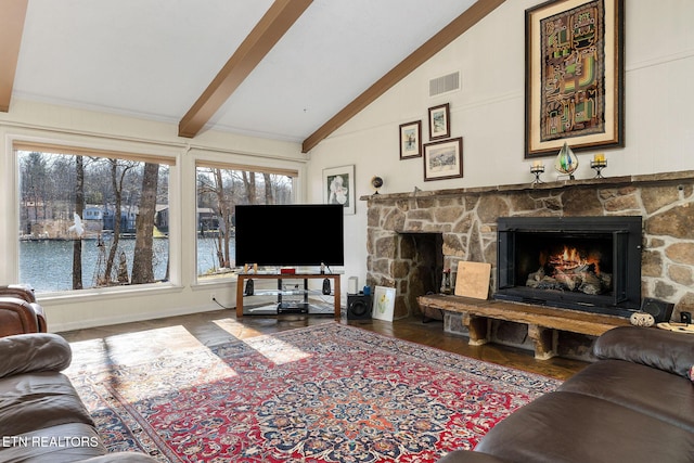 living area with visible vents, a stone fireplace, wood finished floors, high vaulted ceiling, and beamed ceiling