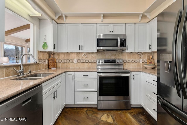 kitchen with white cabinets, tasteful backsplash, stainless steel appliances, and a sink