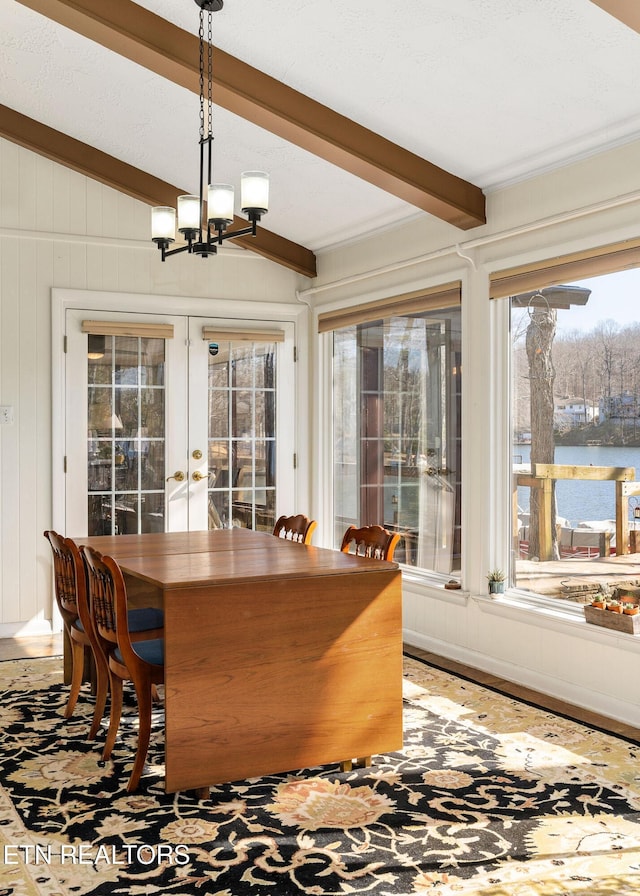 dining room featuring lofted ceiling with beams, wooden walls, wood finished floors, french doors, and an inviting chandelier