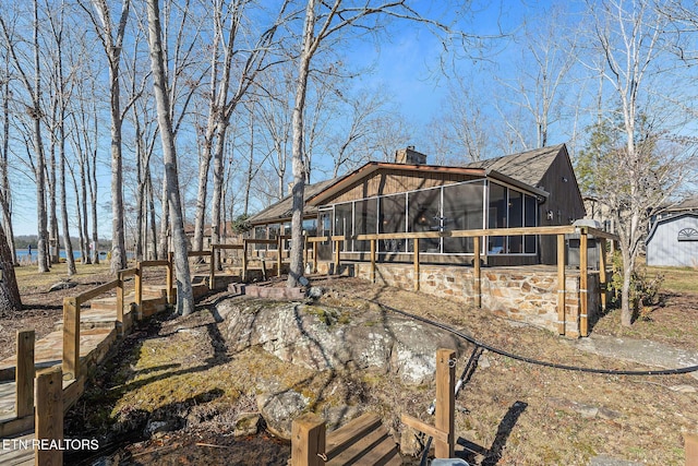 view of property exterior with a sunroom and a chimney