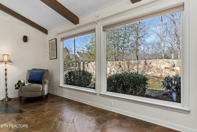 living area featuring lofted ceiling with beams and baseboards